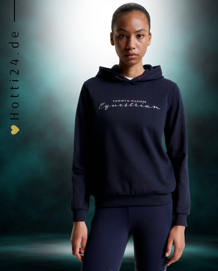 Damen-Hoodie von Tommy Hilfiger mit der Bezeichnung "Metallic TH08WHOO438-004" in der Farbe Blau. Dieser Hoodie ist auf der Webseite www.hotti24.de erhältlich. Er wurde speziell für Damen entworfen, um sowohl Stil als auch Komfort zu bieten. Die Datei enthält auch Bilder des Hoodies aus verschiedenen Blickwinkeln, darunter die Vorderseite, die Seite und die Rückseite. Diese visuellen Darstellungen ermöglichen es Ihnen, das Design und die Eigenschaften des Hoodies besser zu verstehen